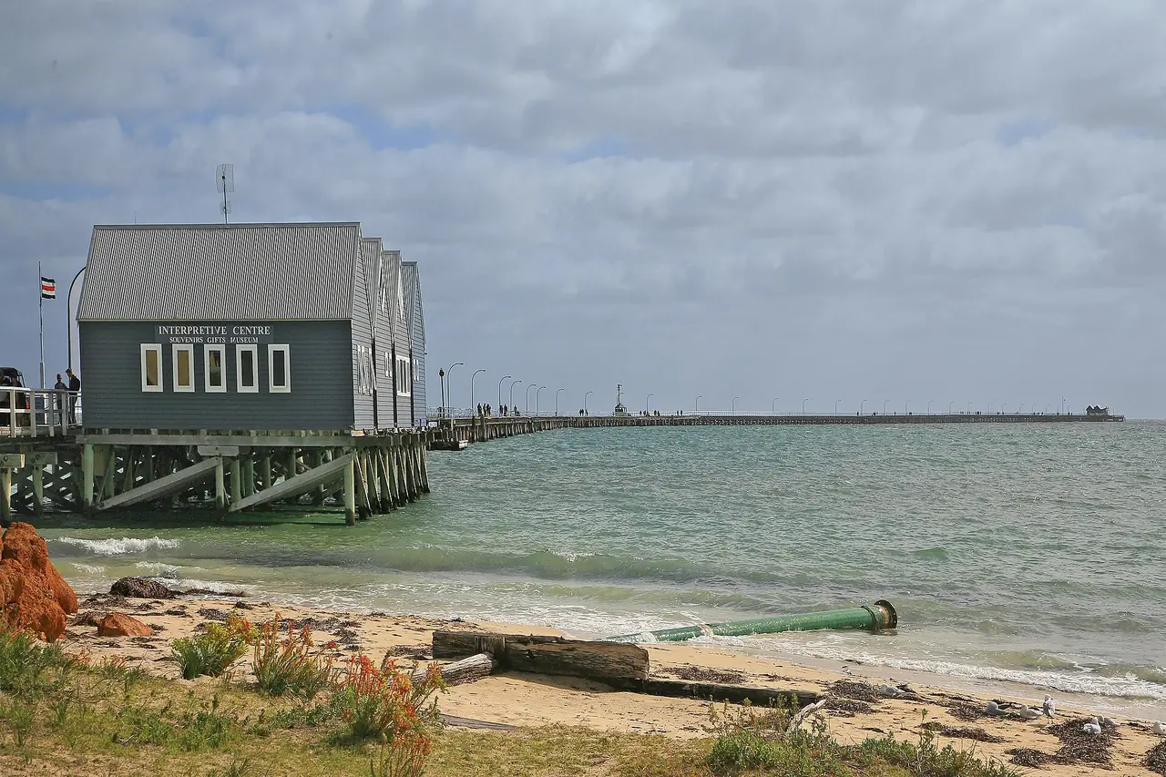 ท่าเรือไม้ Busselton Jetty ยื่นออกไปในอ่าว Geographe พร้อมอาคารศูนย์ข้อมูลที่ต้นสะพาน ภาพจาก Wikimedia Commons ผู้ถ่าย W. Bulach สัญญา CC BY-SA 4.0 ไม่ระบุปีที่ถ่าย