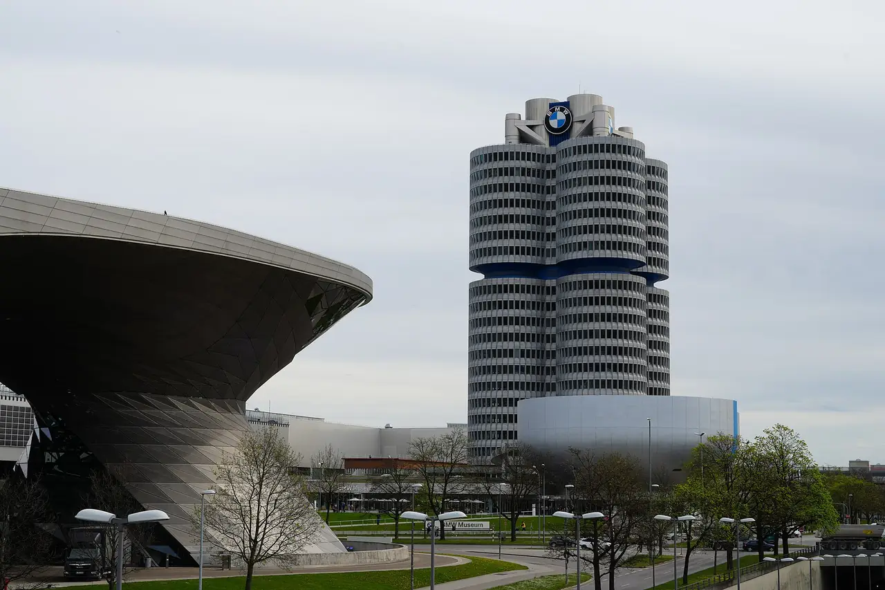 ตึก BMW Vierzylinder สำนักงานใหญ่ทรงสี่กระบอกสูบ ข้างอาคาร BMW Welt ภาพจาก Wikimedia Commons ผู้ถ่าย Strubbl สัญญา CC BY-SA 4.0 ถ่ายเมษายน 2568
