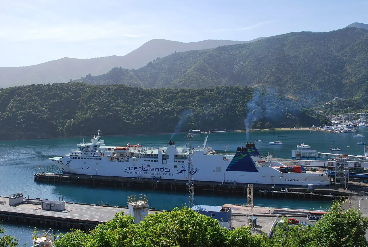 เรือเฟอร์รี Interislander เทียบท่าที่ Picton มีเนินเขาและอ่าวเป็นฉากหลัง ภาพจาก Wikimedia Commons ผู้ถ่าย Mattinbgn สัญญา CC BY 3.0 เป็นภาพเก่า เรือที่ให้บริการในปัจจุบันอาจไม่ใช่ลำเดียวกัน