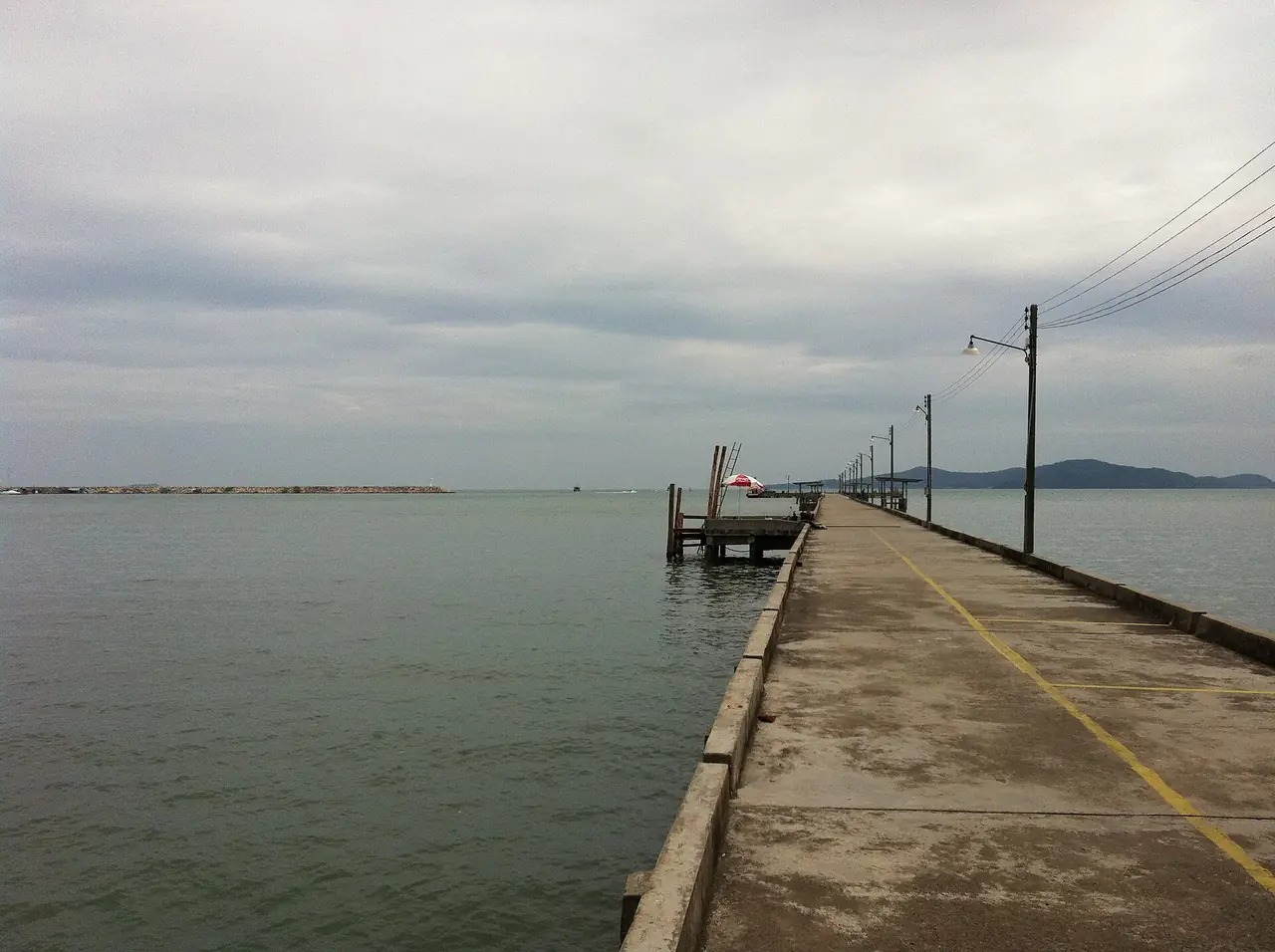 สะพานท่าเรือคอนกรีตยื่นลงทะเลที่ตำบลเพ อำเภอเมืองระยอง ภาพจาก Wikimedia Commons ผู้ถ่าย Mozhar สัญญา CC BY-SA 3.0 เป็นภาพเก่าจากชุดพาโนรามิโอ ไม่ได้ลงวันที่ เป็นภาพประกอบย่านเดียวกับตลาดบ้านเพ