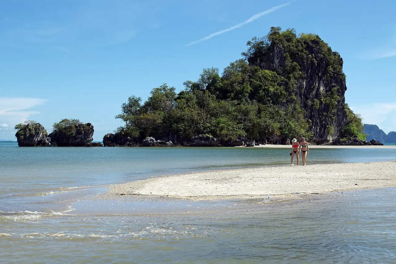 หาดนพรัตน์ธารา มีสันทรายขาวทอดไปยังเกาะหินปูนเล็ก ๆ ที่มีต้นไม้ปกคลุม และคนสองคนเดินอยู่บนสันทราย ภาพจาก Wikimedia Commons ผู้ถ่าย kallerna สัญญา CC BY-SA 3.0 ตามชื่อไฟล์ ไม่ระบุปีที่ถ่ายและไม่ระบุระดับน้ำ เป็นภาพประกอบ หน้าตาขึ้นกับระดับน้ำวันนั้น