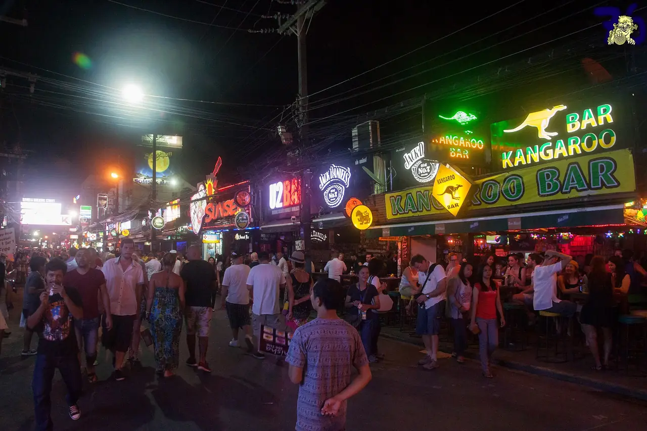ซอยบางลาตอนกลางคืนคนแน่นหน้าร้านบาร์ที่มีป้ายไฟหลายร้าน ภาพจาก Wikimedia Commons ผู้ถ่าย Ben Reeves from Phuket, Thailand สัญญา CC BY 2.0 ถ่ายเมื่อ 17 ก.พ. 2558 เวลา 21.23 น. ตามคำบรรยายไฟล์ เป็นภาพประกอบ ร้านอาจเปลี่ยนไปแล้ว