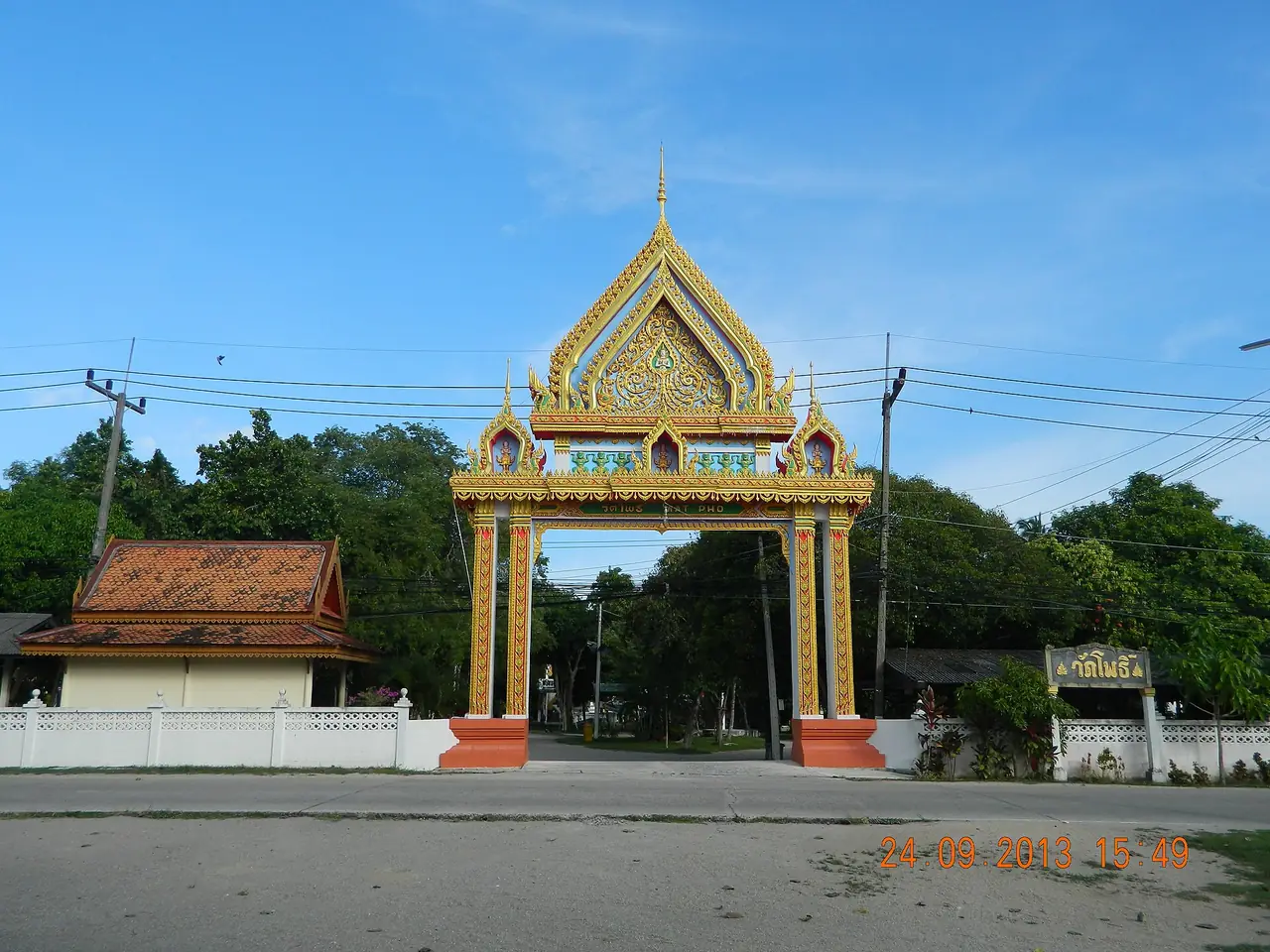 ซุ้มประตูทางเข้าวัดโพธิ์ ตำบลบ้านใต้ เกาะพะงัน ทาสีส้มทองเหนือถนน มีป้ายชื่อวัดอยู่ด้านขวา ภาพถ่ายวันที่ 24 ก.ย. 2556 ตามวันที่ที่ติดในภาพ ชื่อไฟล์บน Commons มีคำว่า Herbal Sauna ท้ายชื่อ แต่เรายังไม่ยืนยันว่าซาวน่าที่ใช้อยู่ตอนนี้อยู่ในวัดนี้ ภาพจาก Wikimedia Commons ผู้ถ่าย Леонид Каратасков สัญญา CC BY-SA 3.0