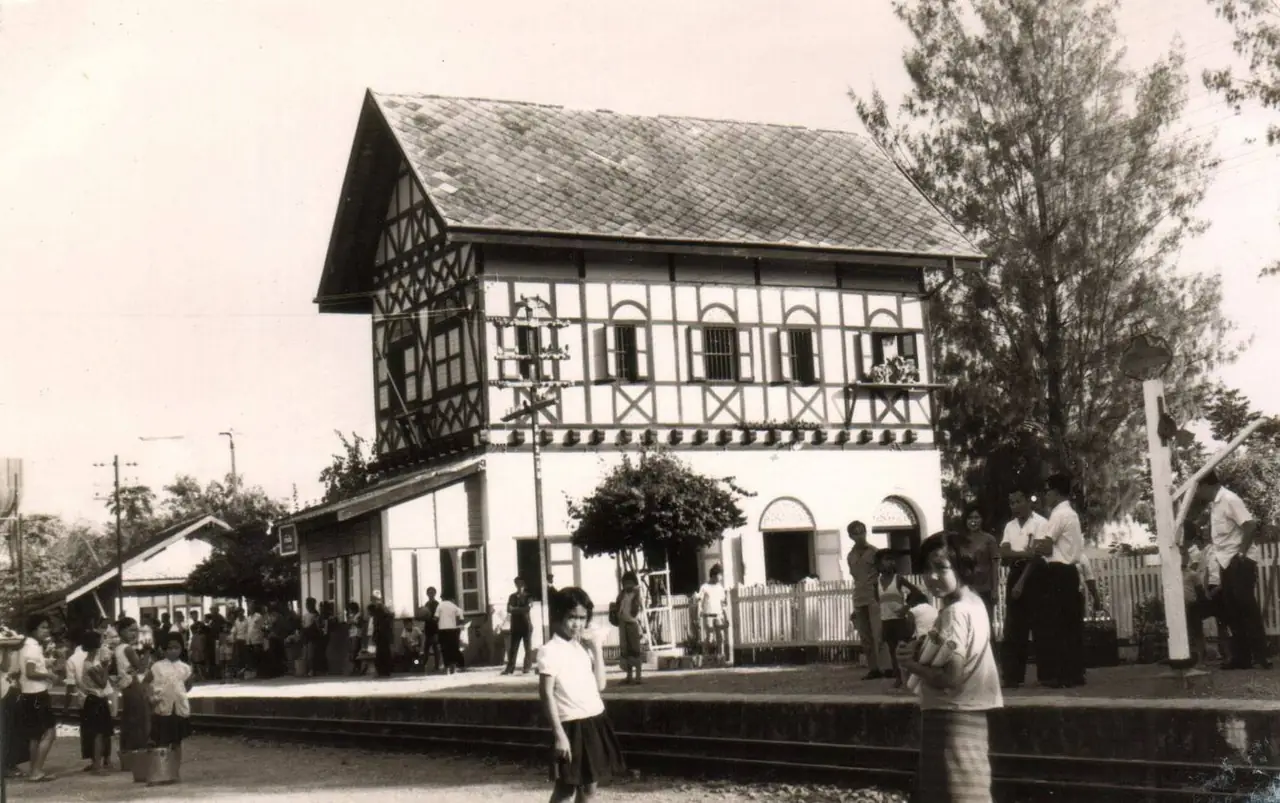 อาคารสถานีบ้านปินและผู้คนบนชานชาลาราวปี ค.ศ. 1967 ภาพเก่าจากหอจดหมายเหตุแห่งชาติที่อยู่ใน Wikimedia Commons สัญญา CC BY-SA 4.0 ปีตามคำอธิบายของไฟล์