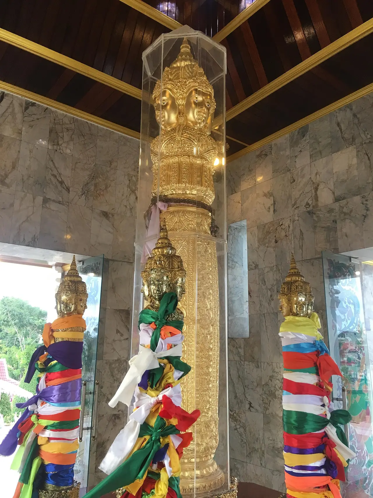 ภายในศาลหลักเมืองสุราษฎร์ธานี เห็นเสาทองที่ยอดเป็นพระพักตร์หลายหน้า มีผ้าแพรหลากสีผูกอยู่ ภาพจาก Wikimedia Commons ผู้ถ่าย Christophe95 สัญญา CC BY-SA 4.0 ไม่ระบุปีที่ถ่าย